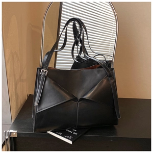 Dettaglio della borsa tote in pelle nera opaca con un design a piega geometrica a busta