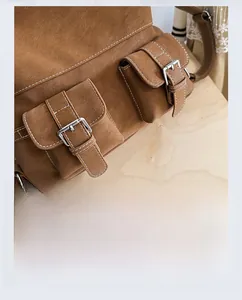 Close-up of brown vintage leather backpack featuring white stitching and silver buckles