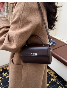 Sac à main carré marron foncé avec fermoir rotatif argenté porté dans un décor d'automne