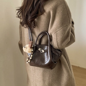 Detail of dark brown vintage bucket bag with silver lock and plush bear charm
