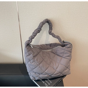 Detail of quilted tote bag featuring a pleated cloud handle and smooth metal zipper