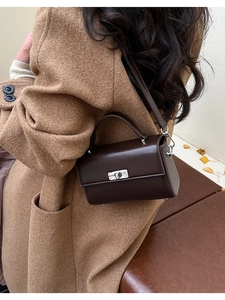 Détail d'un sac bandoulière en cuir marron foncé avec boucle argentée et poignée