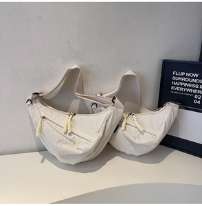 Detail view of large minimalist cream canvas crescent bags with wide adjustable straps