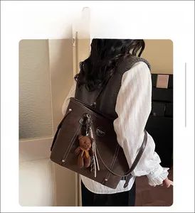 Dark brown tote bag with bear charm shown from the back on a female model in casual setting
