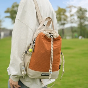 Dettaglio dello zaino a coulisse con patchwork a scacchi arancioni e ciondolo tennis