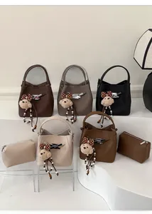 Detailed display of five bucket bags in various colors with bear charms and coin purses