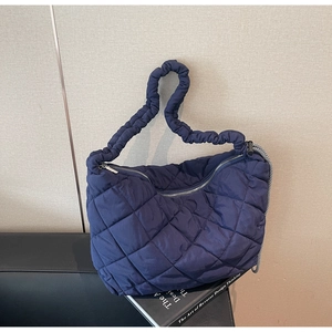 Detail of navy quilted nylon tote with ruched strap and checkerboard pattern ribbon