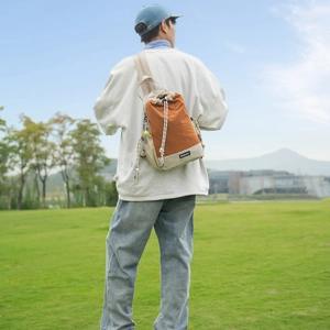 Scatto lifestyle di una borsa in tela arancione e beige capiente con coulisse esterna