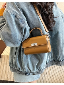 Détail du sac à main en cuir caramel avec fermoir rotatif argenté sur veste en jean