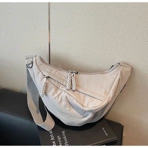Detail view of beige nylon crescent bag with woven zipper pulls and wide strap