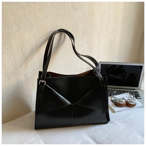 Dettaglio della borsa tote in pelle nera con patta geometrica e tracolla regolabile