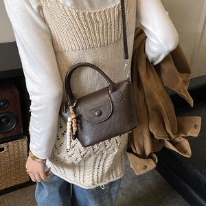 Detail view of dark brown PU leather crossbody bag with vintage bead charm and strap