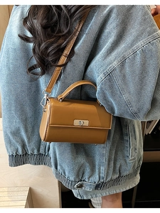 Back view of model wearing a brown crossbody bag with silver buckle and denim jacket