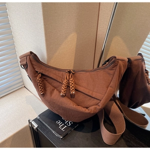Detailed view of brown nylon half-moon bag featuring woven zipper pulls and wide strap