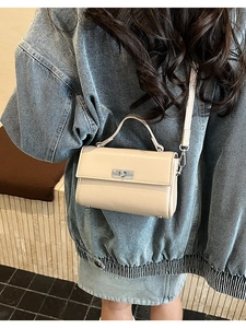 Détail du mini sac carré crème avec fermoir rotatif argenté et texture en cuir lisse