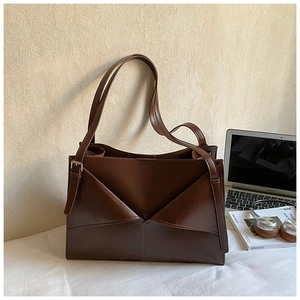 Borsa tote in pelle marrone con piega geometrica e tracolla regolabile su scrivania