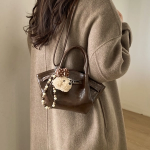 Detail view of brown faux leather bucket bag with cute bear charm and beaded chain accessory
