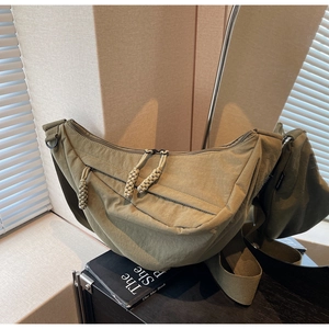 Detail of olive green crescent crossbody bag showing nylon texture and rope zipper pull
