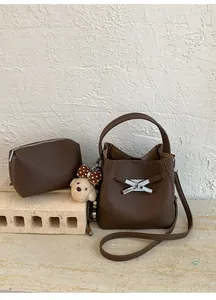 Detail of dark brown leather bucket bag with silver hardware and a cute bear charm