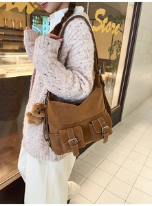 Detail of caramel brown suede tote bag with double front pockets and teddy bear charm