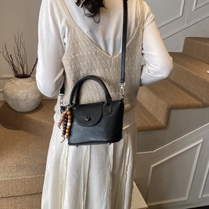 Detail of black matte leather handbag with magnetic flap and beaded tassel charm