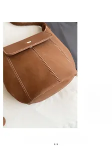 Close-up of brown litchi pattern leather bag with white stitching and gold metal buckle