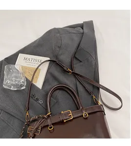 Detail of dark brown leather bucket bag with gold hardware and adjustable strap