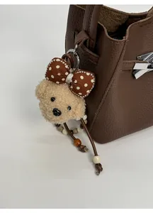 Detail of plush bear charm with polka dot bow on lychee texture leather bucket bag
