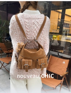 Detail of a brown vintage faux leather backpack with side pockets and a cute bear charm