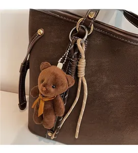 Close-up of deep brown pebbled leather tote bag with a cute plush teddy bear charm