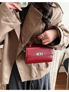 Détail du sac bandoulière en cuir rouge avec fermoir rotatif en métal sur le mannequin