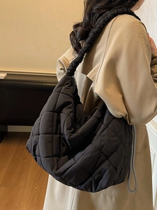 Black quilted puffer tote bag with ruched shoulder strap shown on model in a modern setting