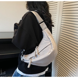 Detail of light grey nylon crescent bag with woven rope zippers and wide shoulder strap