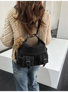 Detail of black nylon tote bag with white contrast stitching and cute teddy bear charm