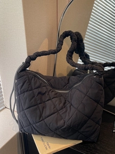 Quilted black tote bag with ruffled handles and diamond stitching for stylish daily commute