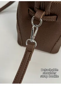 Detail of the detachable shoulder strap with silver metal clasp on lychee leather bucket bag
