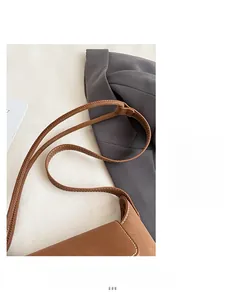 Detail view of brown leather bucket bag with white decorative stitching and slim strap