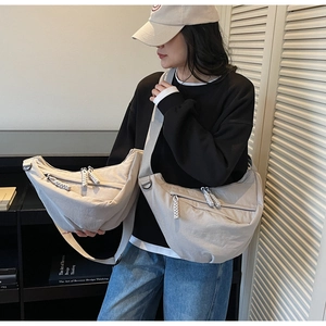 Detail of light gray nylon crescent bags in two sizes with woven rope zipper pulls