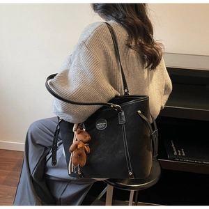 Detail of black tote bag with white contrast stitching and cute plush bear charm
