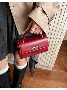 Gros plan d'un sac à main bordeaux avec fermoir rotatif argenté et texture en cuir lisse