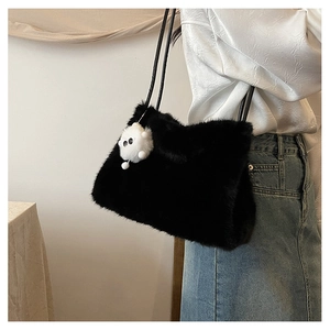 Dettaglio della borsa a secchiello in peluche nera con un simpatico charm mostro bianco
