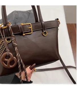 Detail of dark brown pebble leather bag with gold buckle and creative bagel pendant