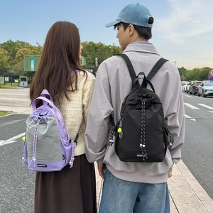 Vista lifestyle di coppie con zaini in nylon viola e neri con coulisse per esterni