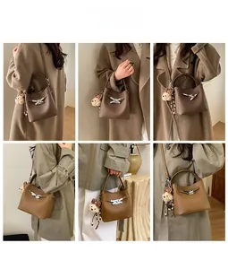 Litchi pattern bucket bag featuring a decorative metal bow and plush bear pendant