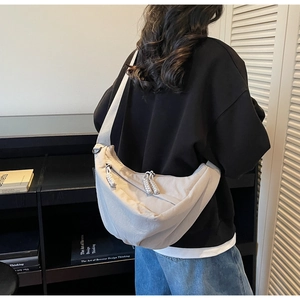 Detail of light beige crescent crossbody bag with woven rope zipper and textured fabric