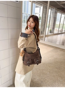 Brown suede tote bag with dual front pockets and plush bear charm on a female model