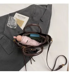 Internal capacity of retro brown crossbody bag showing umbrella, phone and power bank