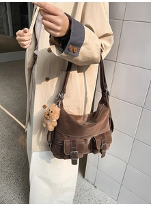 Detailed view of dark brown suede tote bag with utility pockets and plush bear charm