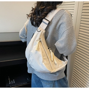 Detail of off-white crescent crossbody bag with woven zipper and adjustable strap