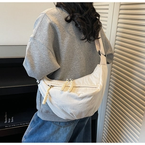 Detail of off-white crescent crossbody bag featuring lightweight nylon and woven zipper pull